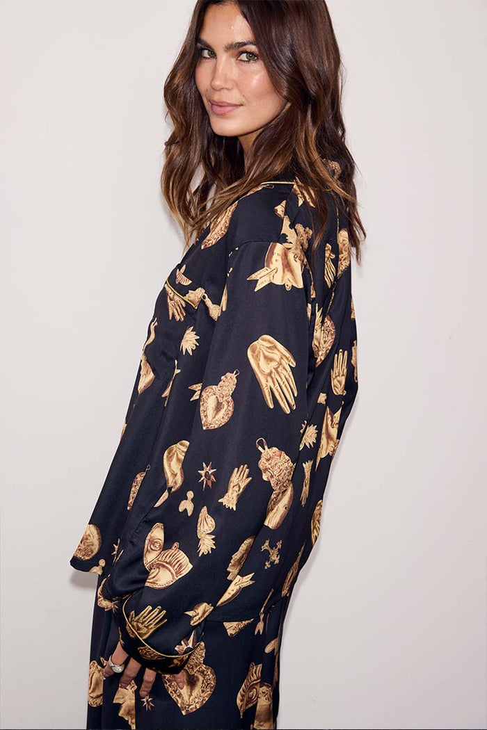 Deloris Button Through Pyjamas in black featuring gold hand and heart motifs, worn by a model looking over her shoulder.
